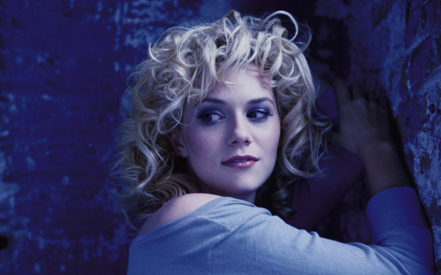 Blonde woman wall posing promotional free wallpaper for desktop - medium preview image