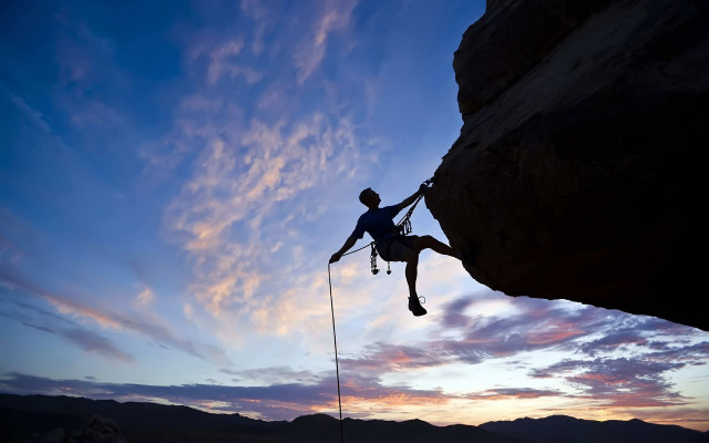 Man climbing cliff sunset sky free wallpaper for desktop - medium preview image