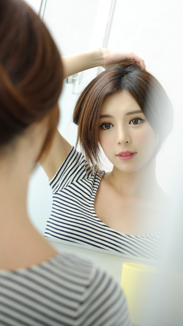Woman looking mirror holding hair free wallpaper for mobile - medium preview image
