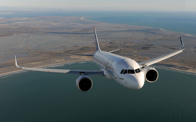 Jetliner over ocean beach town free wallpaper for desktop - medium preview image