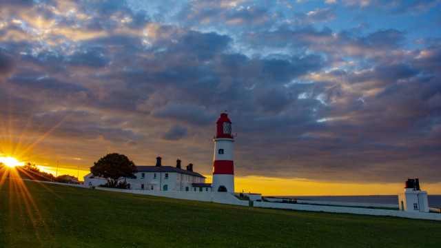 Lighthouse grassy hill sunset clouds free wallpaper for desktop - medium preview image