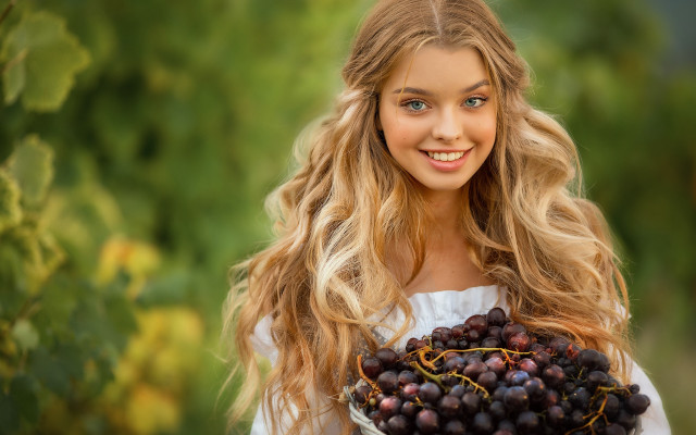 Woman grinning holding grapes outdoors free wallpaper for desktop - medium preview image