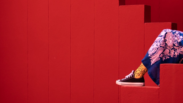 Person sitting red wall sneakers free wallpaper for desktop - medium preview image