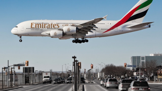 Emirates jetliner over busy street free wallpaper for desktop - medium preview image