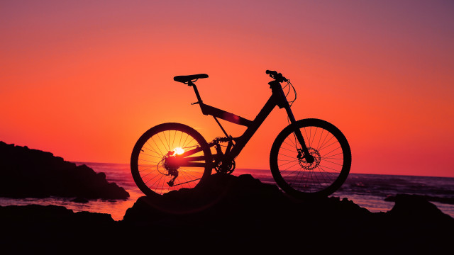 Bike parked rock sunset ocean free wallpaper for desktop - medium preview image