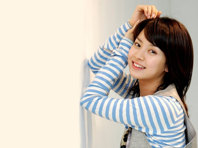 Smiling woman leaning wall hand free wallpaper for desktop - medium preview image