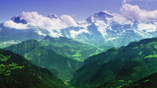 Mountain range green clouds sky - a view of a mountain range free wallpaper