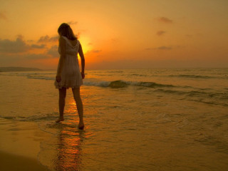 Woman standing water beach sunset - the sun setting behind her free wallpaper for desktop