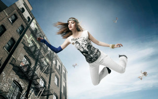 Woman jumping kite building birds - her hand and a building in the background free wallpaper