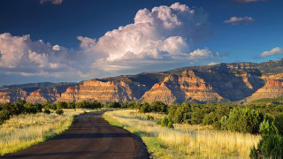Mountain road grass field sky - a grassy field in the foreground free wallpaper