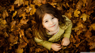 Smiling girl lying autumn leaves - a little girl free wallpaper