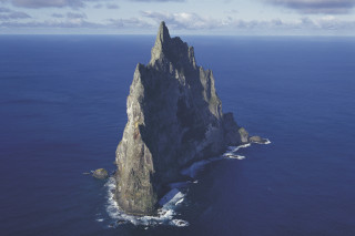 Large rock formation ocean boat - land art free wallpaper