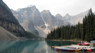 Canoes docked lake mountains snow - the top of the mountains free wallpaper