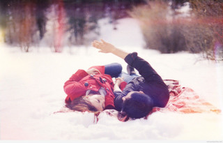 Couple lying snow blanket reaching - claire hummel free wallpaper