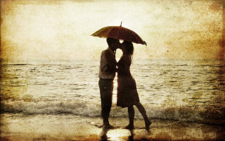 Couple kissing umbrella beach sunset - the ocean in the background free wallpaper