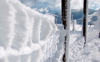 Fence covered snow piled mountain - an abstract sculpture free wallpaper