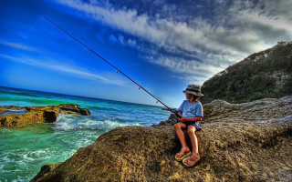 Man sitting rock fishing ocean - a fishing rod free wallpaper