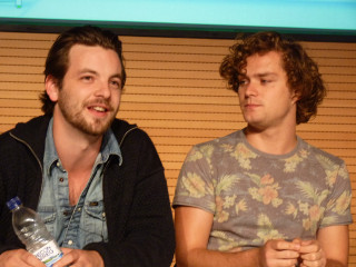 Two men sitting holding bottles - each other holding free wallpaper