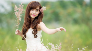 Woman white dress holding flower 2 - a green field in the background free wallpaper