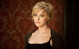 Woman black top jacket red - a red wall behind her free wallpaper