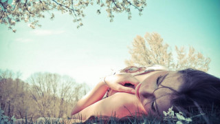 Woman laying grass flowers head - the ground in a field of grass free wallpaper