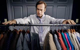 Man standing ties suits closet - a door in the background free wallpaper