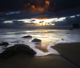 Sunset beach rocks water dark - a sunset over a beach free wallpaper