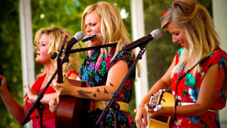 Three women singing microphones guitars - the background and a building in the background free wallpaper