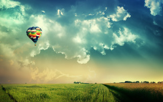 Hot air balloon over lush - a sunbeam in the foreground free wallpaper