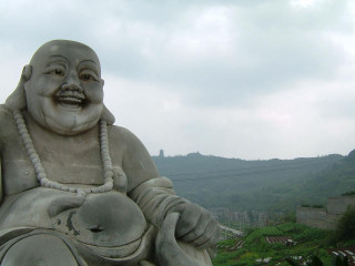 Laughing buddha statue bowl mountain - his hand and a mountain in the background free wallpaper
