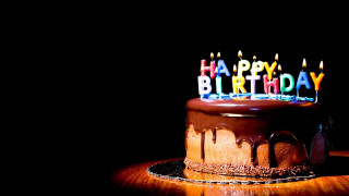 Chocolate birthday cake lit candles 2 - a black backdrop free wallpaper
