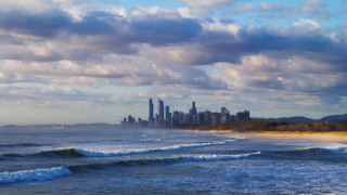 City skyline ocean waves crashing - a beach in the foreground free wallpaper