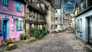 Cobblestone street buildings cloudy sky - both side of it free wallpaper