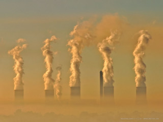 Factory smokestacks emitting distance group - a hazy sky in the background free wallpaper