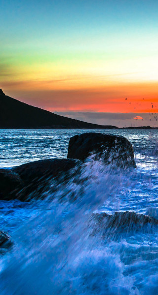 Sunset water mountain crashing wave - a sunset over a body of water free wallpaper for mobile