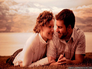 Man woman laying grass smiling - a lake in the background free wallpaper