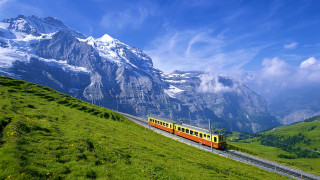 Train traveling tracks mountain range 2 - a green field below free wallpaper for desktop