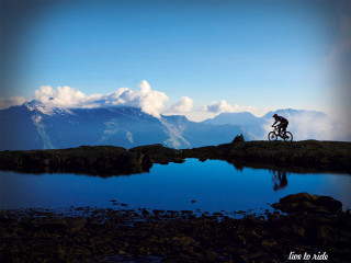 Man riding bike mountain lake 2 - top of a mountain next free wallpaper