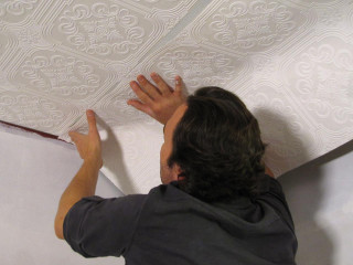 Man painting ceiling white roller - a ceiling free wallpaper