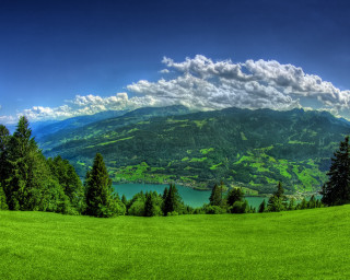 Green field lake mountains clouds - a lake in the middle of it free wallpaper for desktop