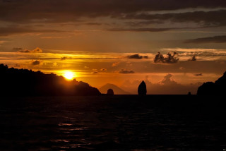 Sunset water mountain boat person - a sunset over a body of water free wallpaper for desktop