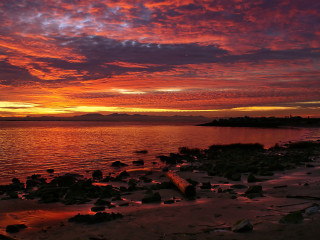Sunset water rocks shore mountain - a sunset over a body of water free wallpaper