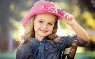 Little girl pink hat smiling 5 - a wooden chair free wallpaper