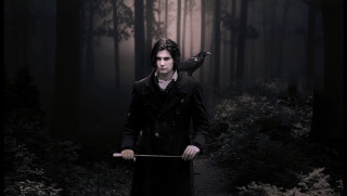 Man long coat holding stick - dark shadow free wallpaper