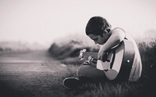 Young boy grass playing guitar - a young boy free wallpaper
