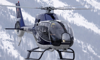 Helicopter flying snow covered mountain - over a snow free wallpaper
