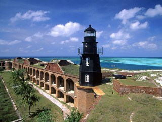 Lighthouse brick wall ocean beach - blue sky in the background free wallpaper