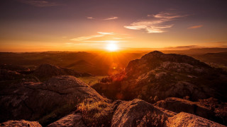 Sunset rocky mountain range bright - a bright sun in the distance free wallpaper