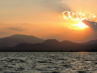 Sunset water mountains boat sunbeam - a sunset over a body of water free wallpaper