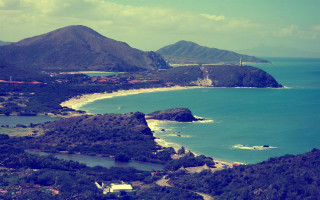 Beach view hilltop water scenery - a lighthouse in the distance free wallpaper